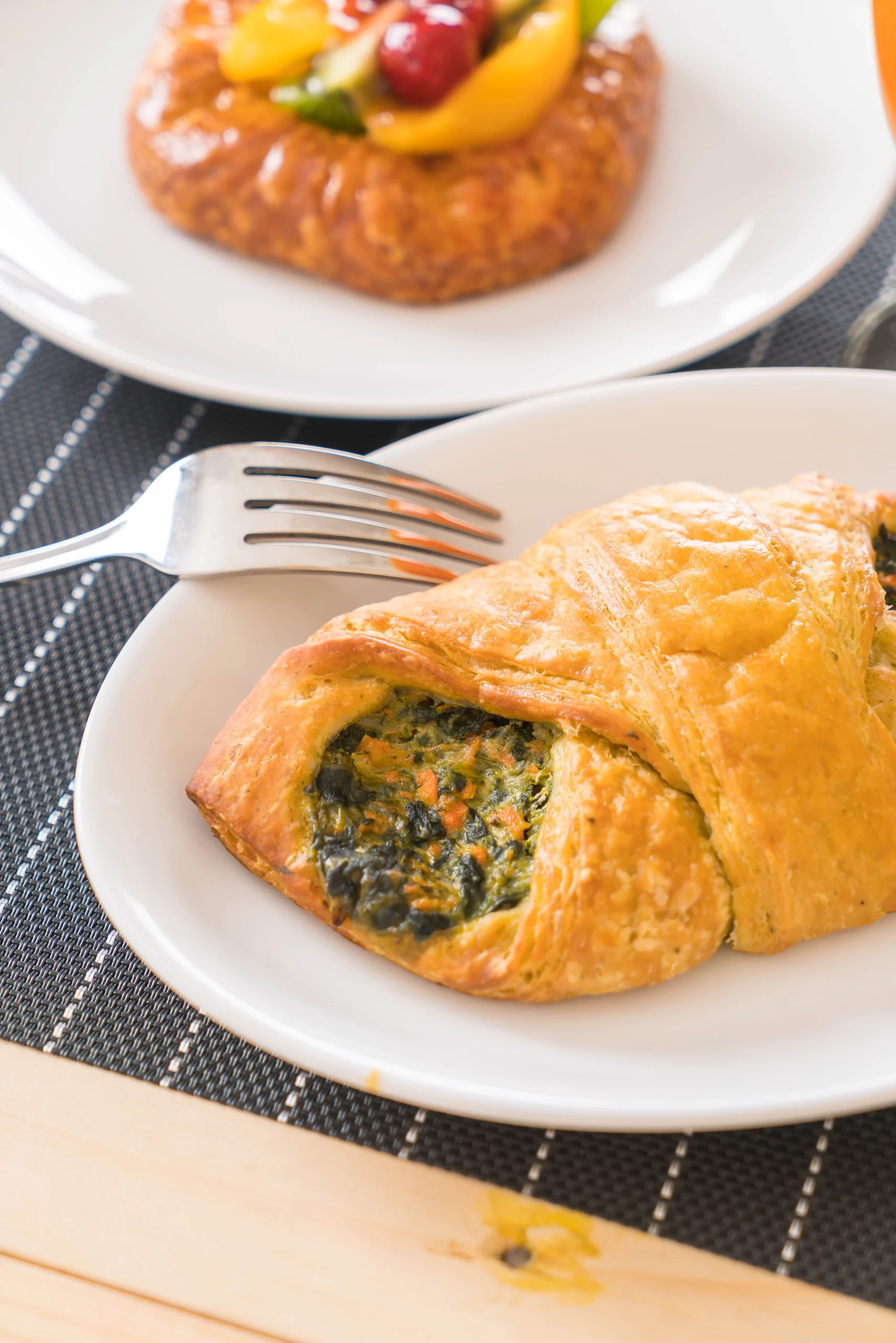 Golden-brown, flaky chicken pastries filled with creamy, seasoned chicken, served on a wooden plate with a side of dipping sauce.